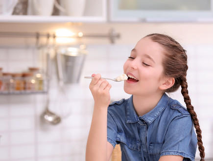 ילדה שמחה נהנת מיוגורט